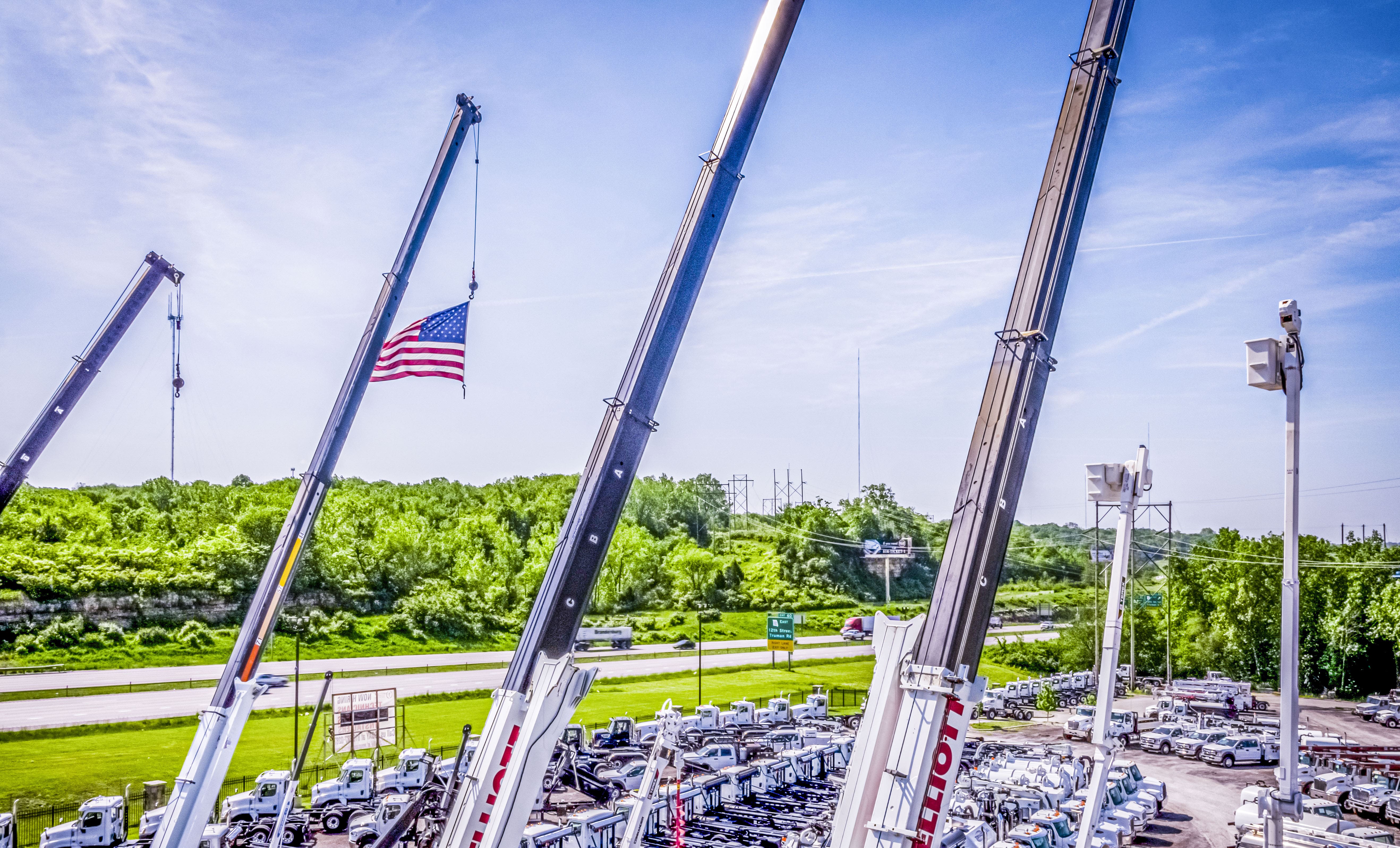 crane booms extended in the air, one holding a U.S. flag