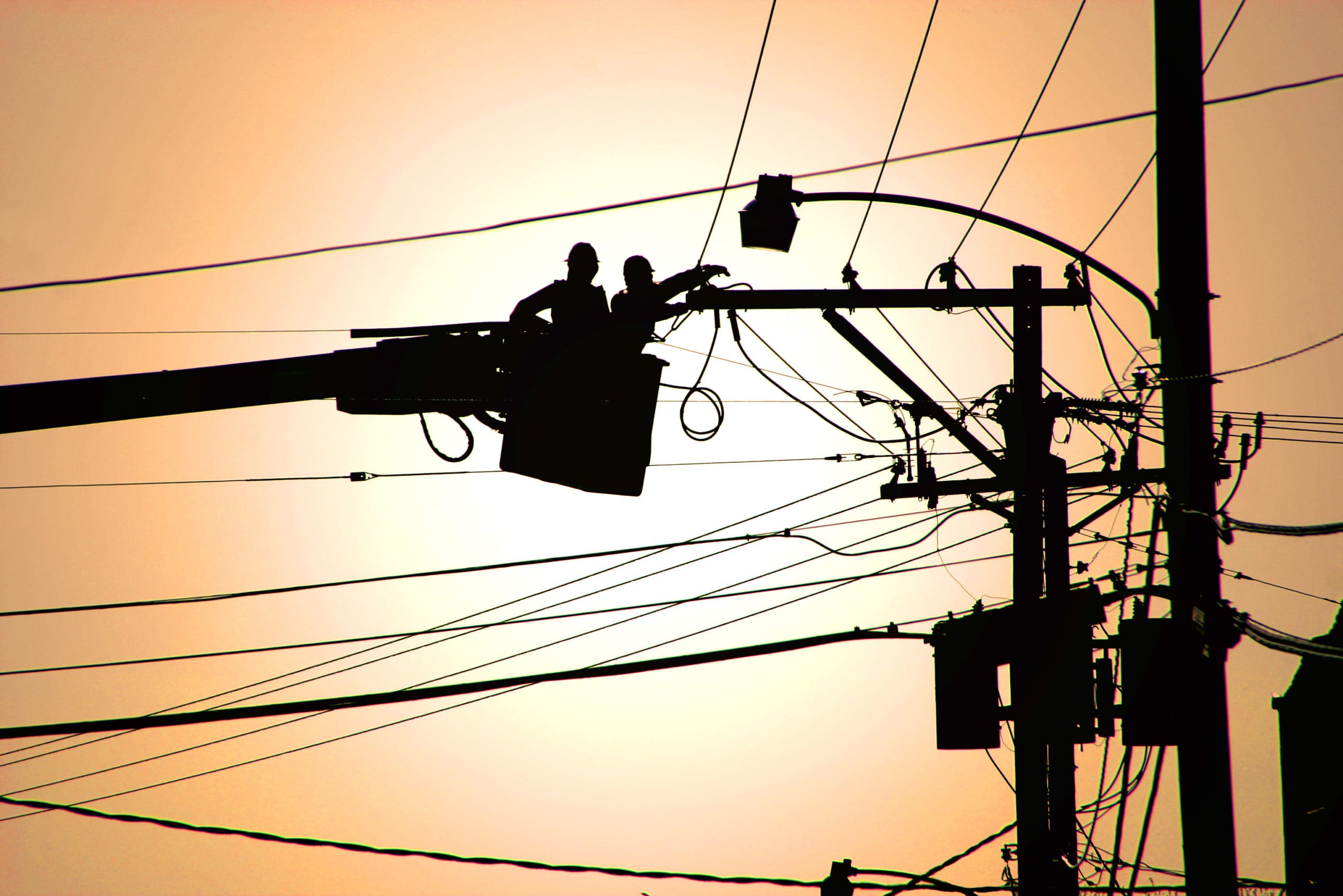 two workers at a utility company in a bucket working on power lines
