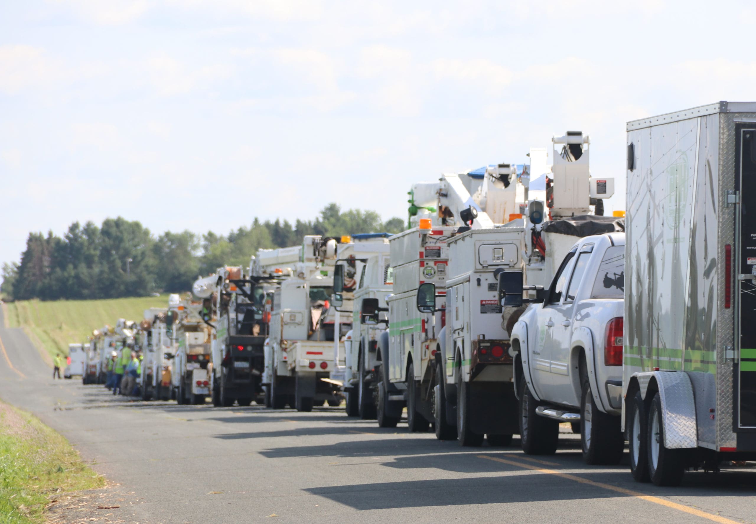 a row of trucks from Regional Mutual Assistance Groups heading down a road to assist with hurricane repairs