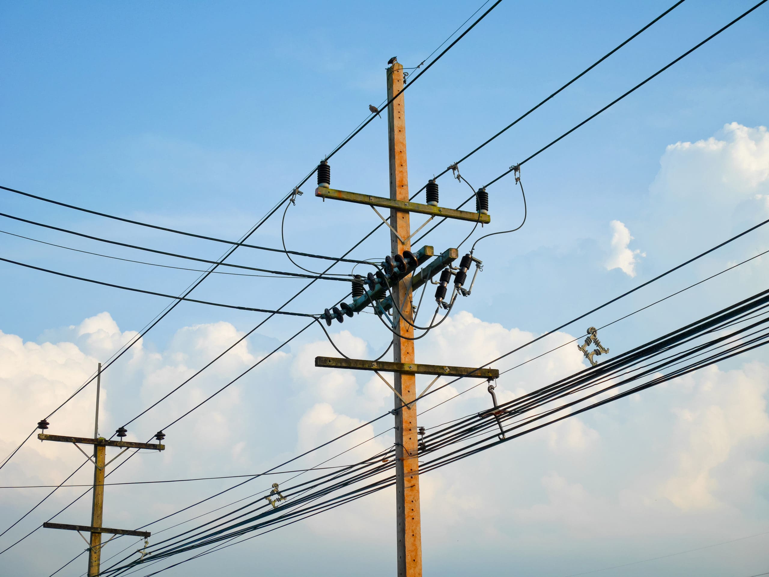 electric distribution poles in front of blue sky