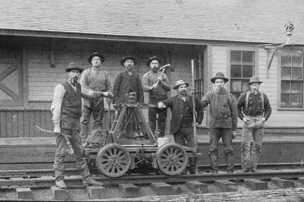black and white photo of old railroaders in front of a handcar