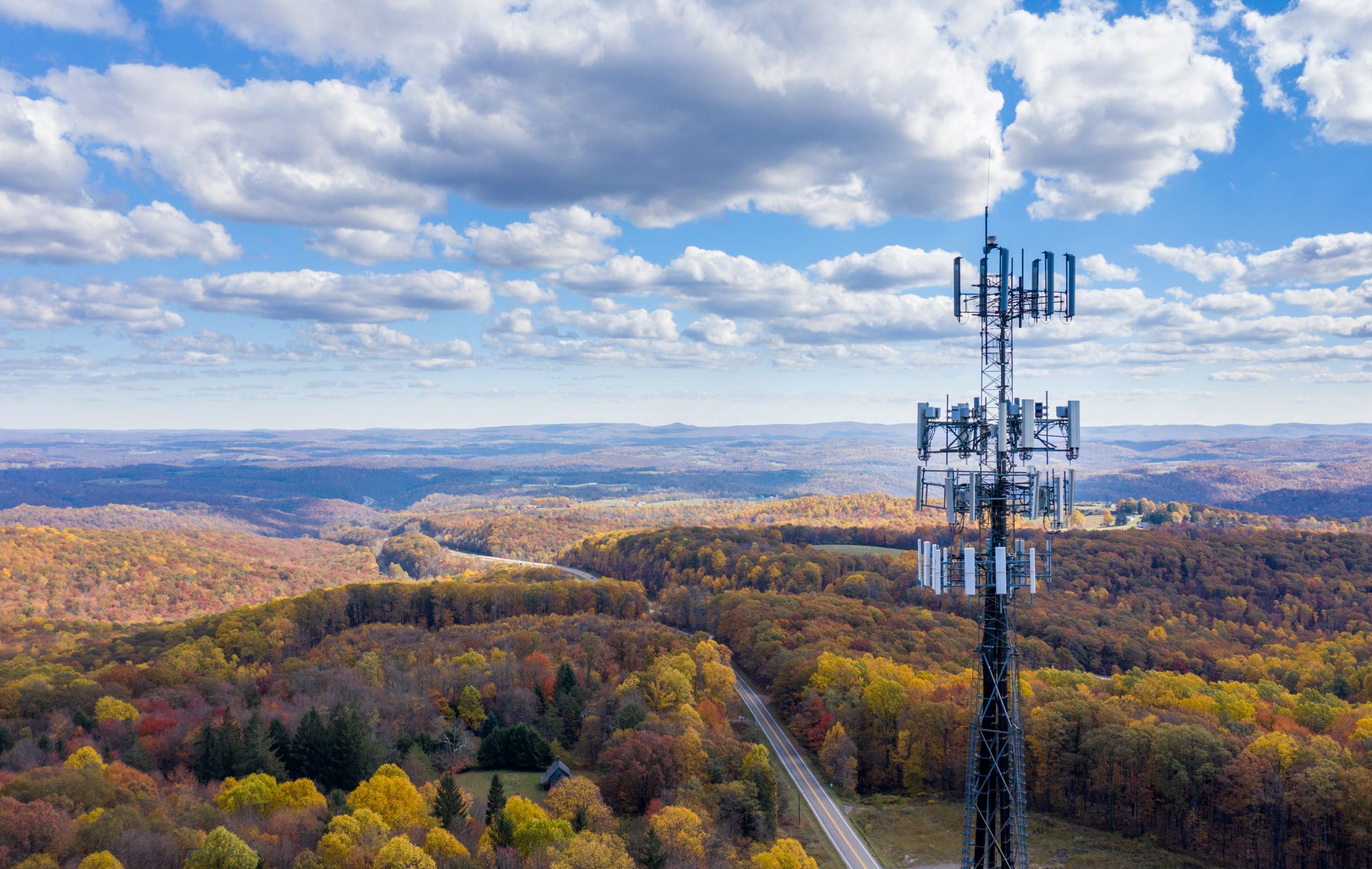 Aerial view of mobile phone cell tower over forested rural area of West Virginia to illustrate lack of broadband internet service