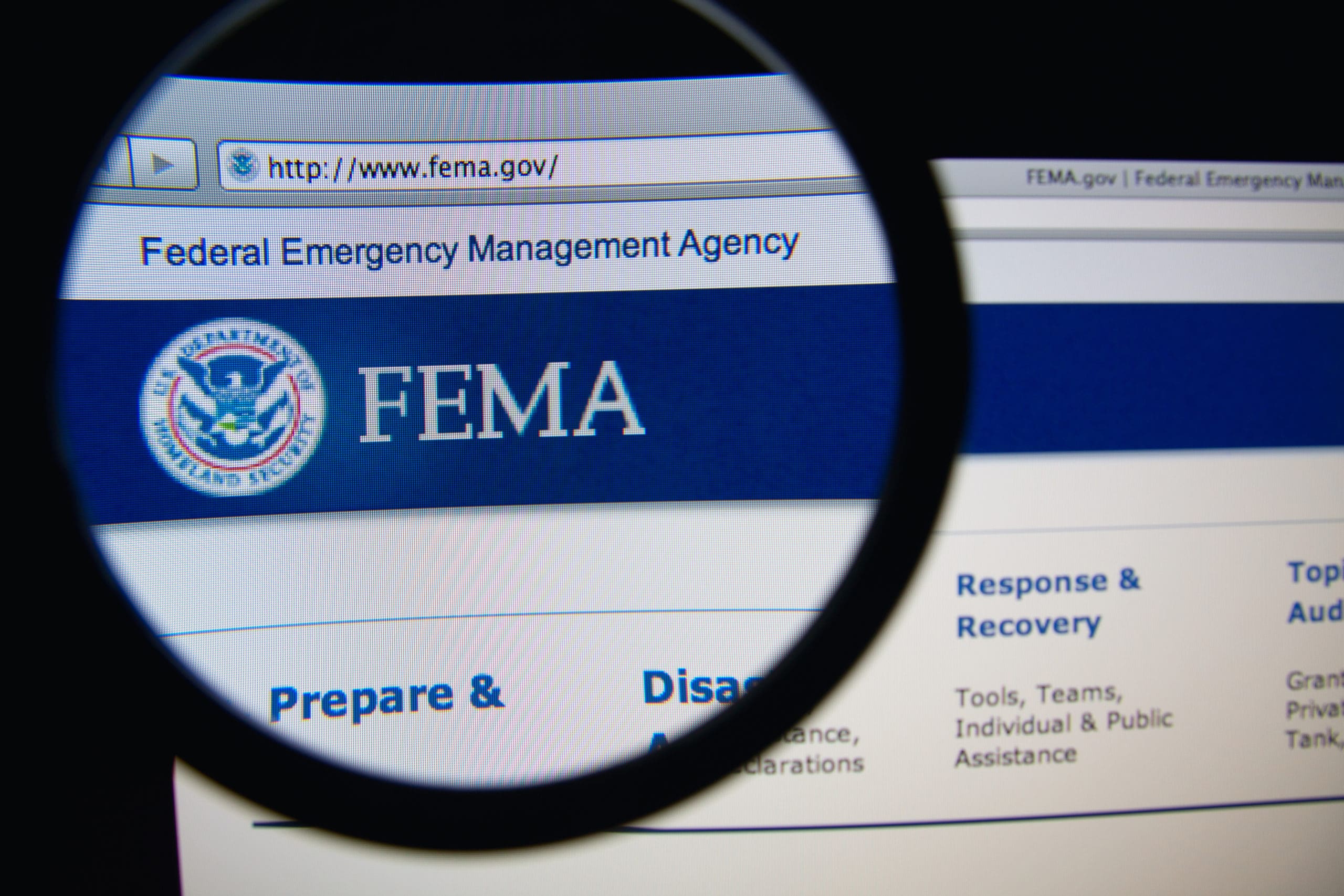 Photo of Federal Emergency Management Agency homepage on a monitor screen through a magnifying glass. FEMA is an agency of the US Department of Homeland Security.